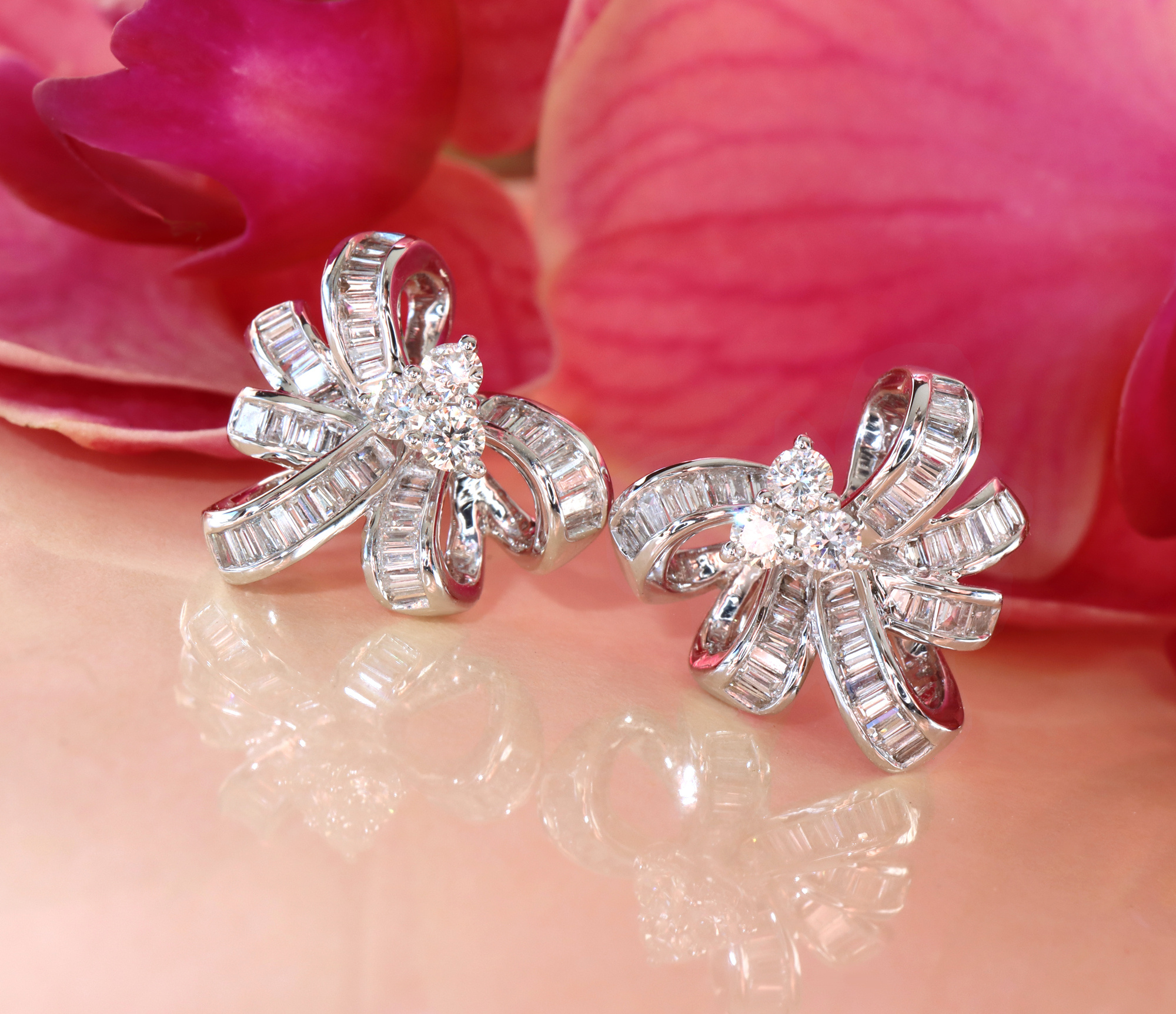 Diamantenschleifen-Ohrstecker in Weißgold, Baguette- und Runddiamanten, vor rosa Blüte liegend