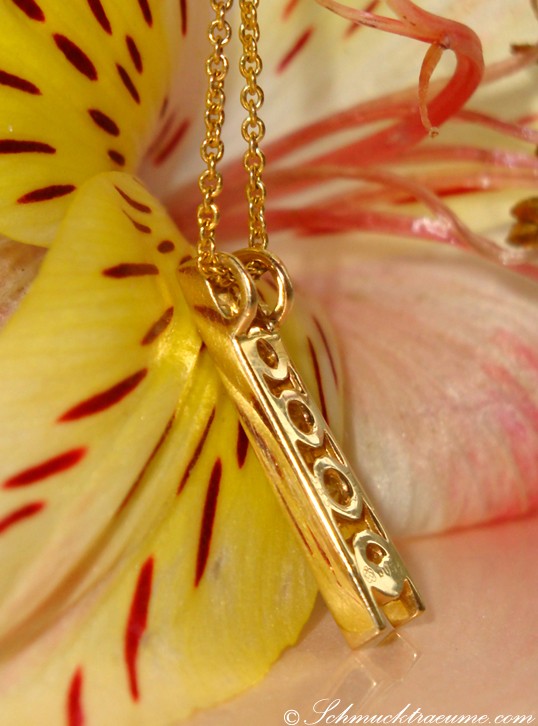 Goldene Kette mit filigranem Anhänger vor Blüte