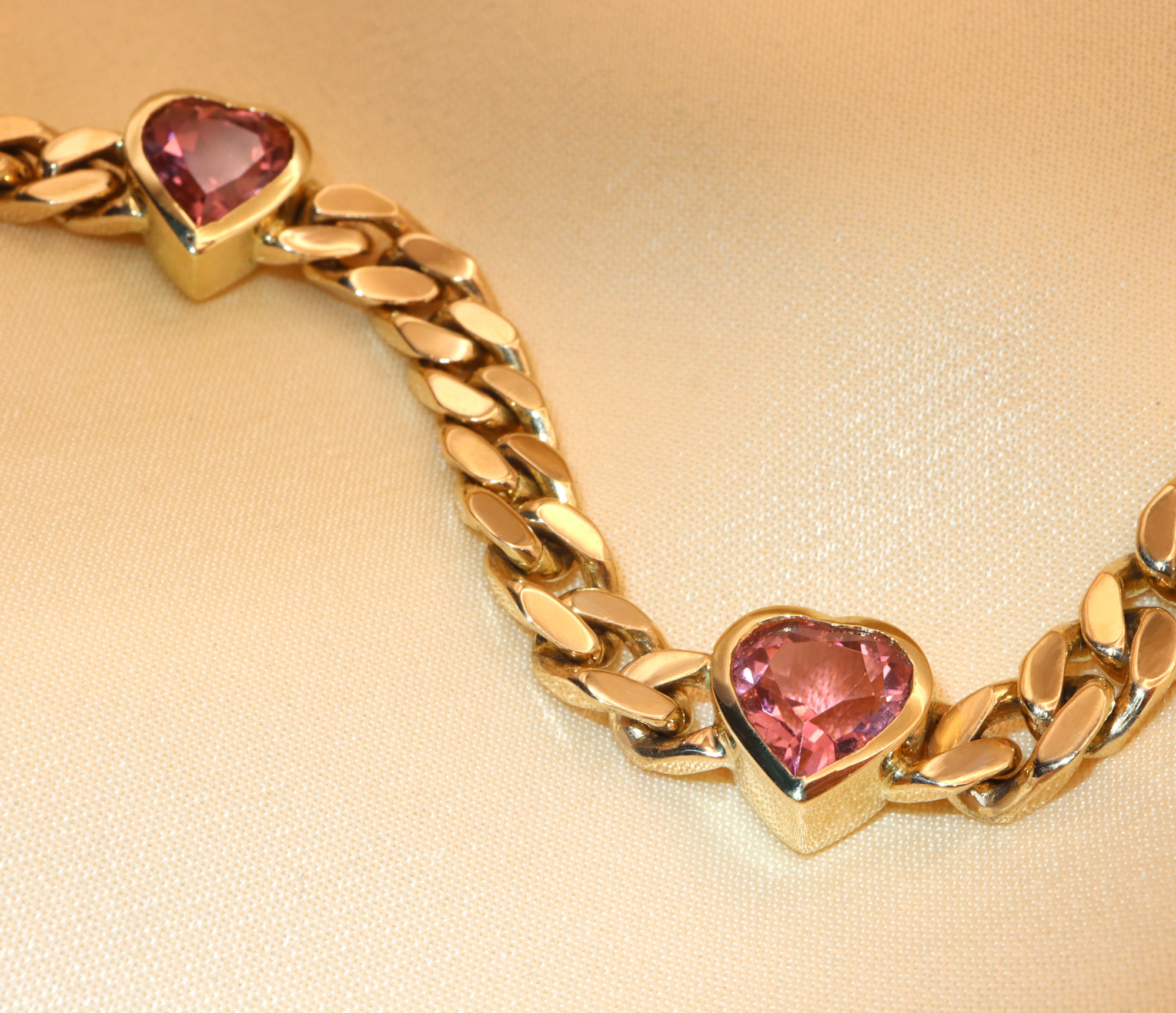 Goldene Panzerarmband mit rosa Turmalin-Herz-Anhänger, detailreiches Design.