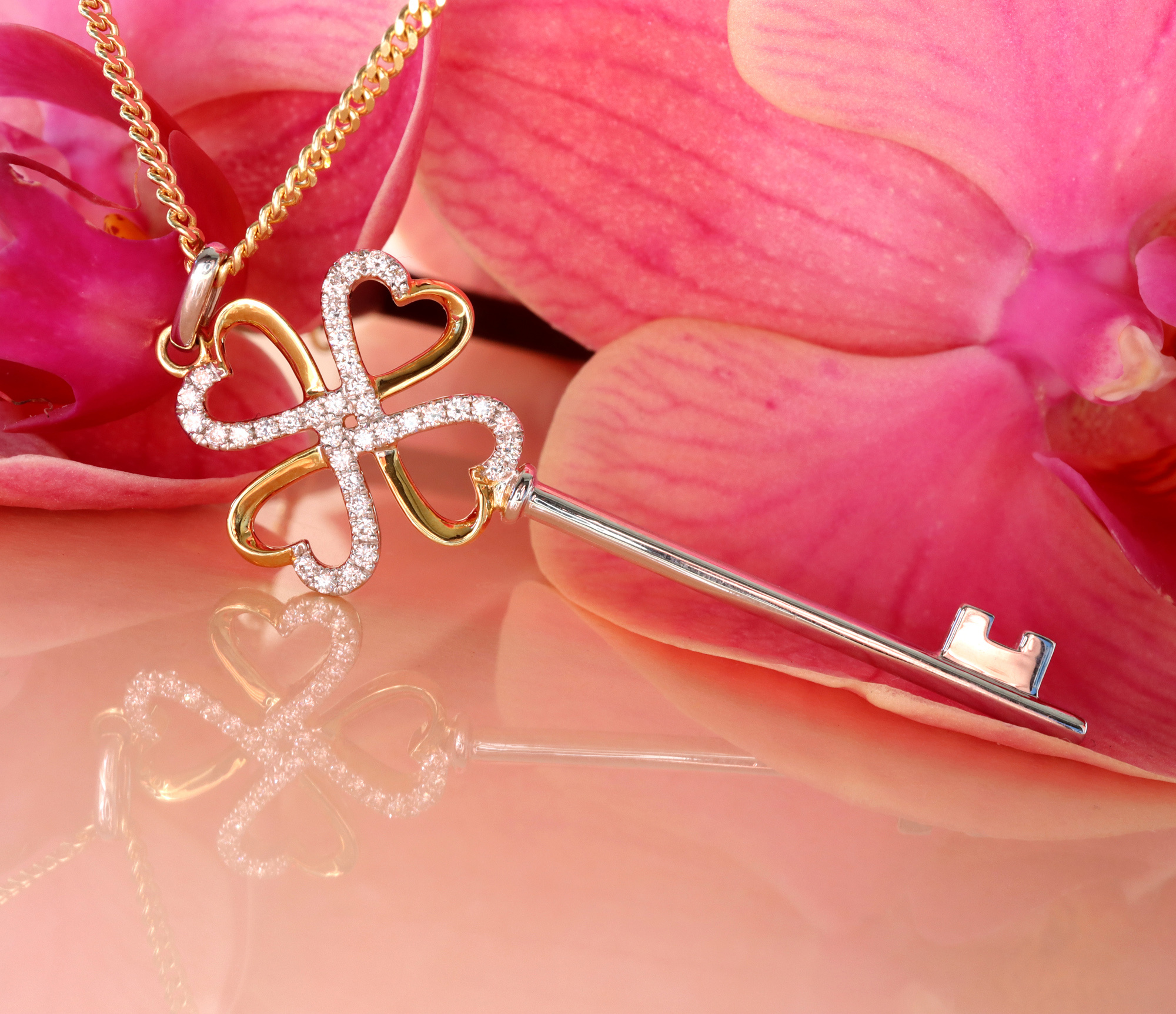 Goldener Schlüsselanhänger mit Brillanten auf rosa Orchidee, Detailaufnahme.