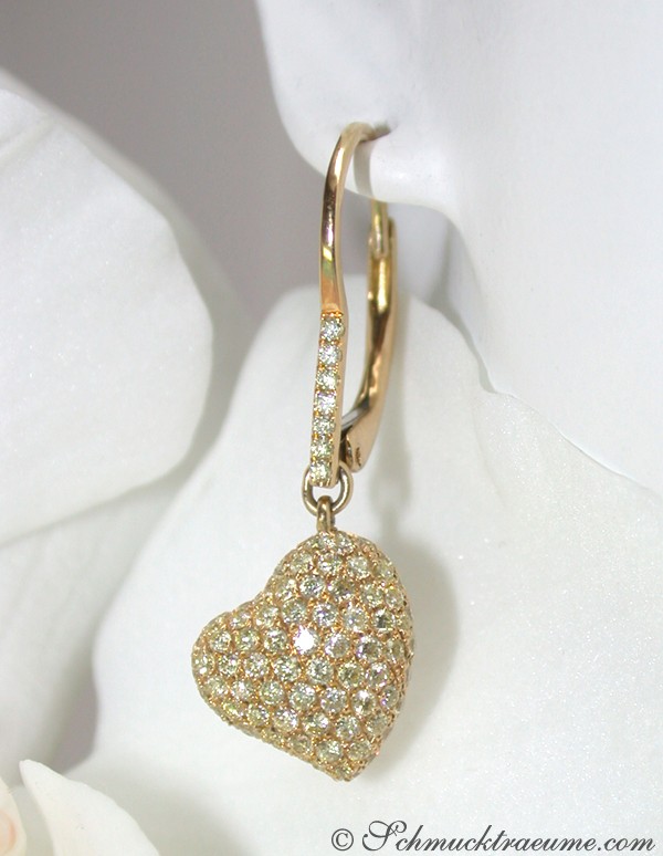 Goldene Herz-Ohrhänger mit Diamanten, getragen auf weißem Hintergrund