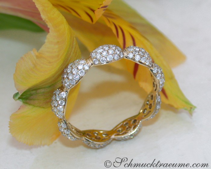 Gelbgoldring mit Brillantpavé, Detailaufnahme, elegant, Blüte im Hintergrund