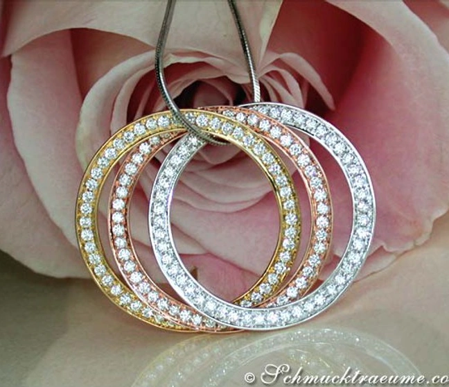 Verflochtene Brillantenkreis-Anhänger im Weißgold, Gelbgold & Roségold vor Rosenblüte Verflochtene Brillantenkreis-Anhänger im Weißgold, Gelbgold & Roségold vor Rosenblüte