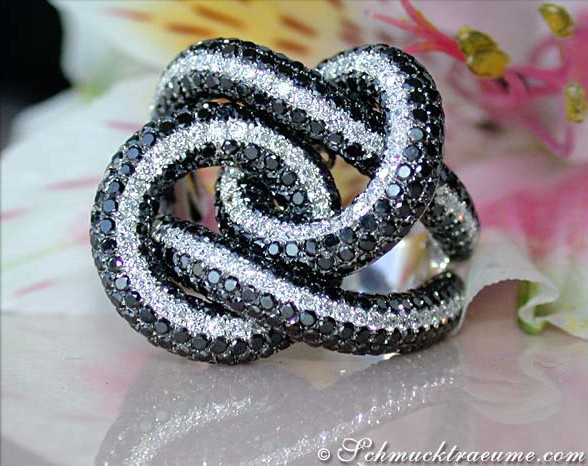 Schwarzer Diamant-Ring mit weißgoldener Verarbeitung, spiralförmig, auf Blütenblättern.