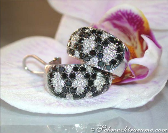 Schwarze und weiße Diamanten im Rauten-Design auf Halbcreolen, auf Orchideenblatt liegend