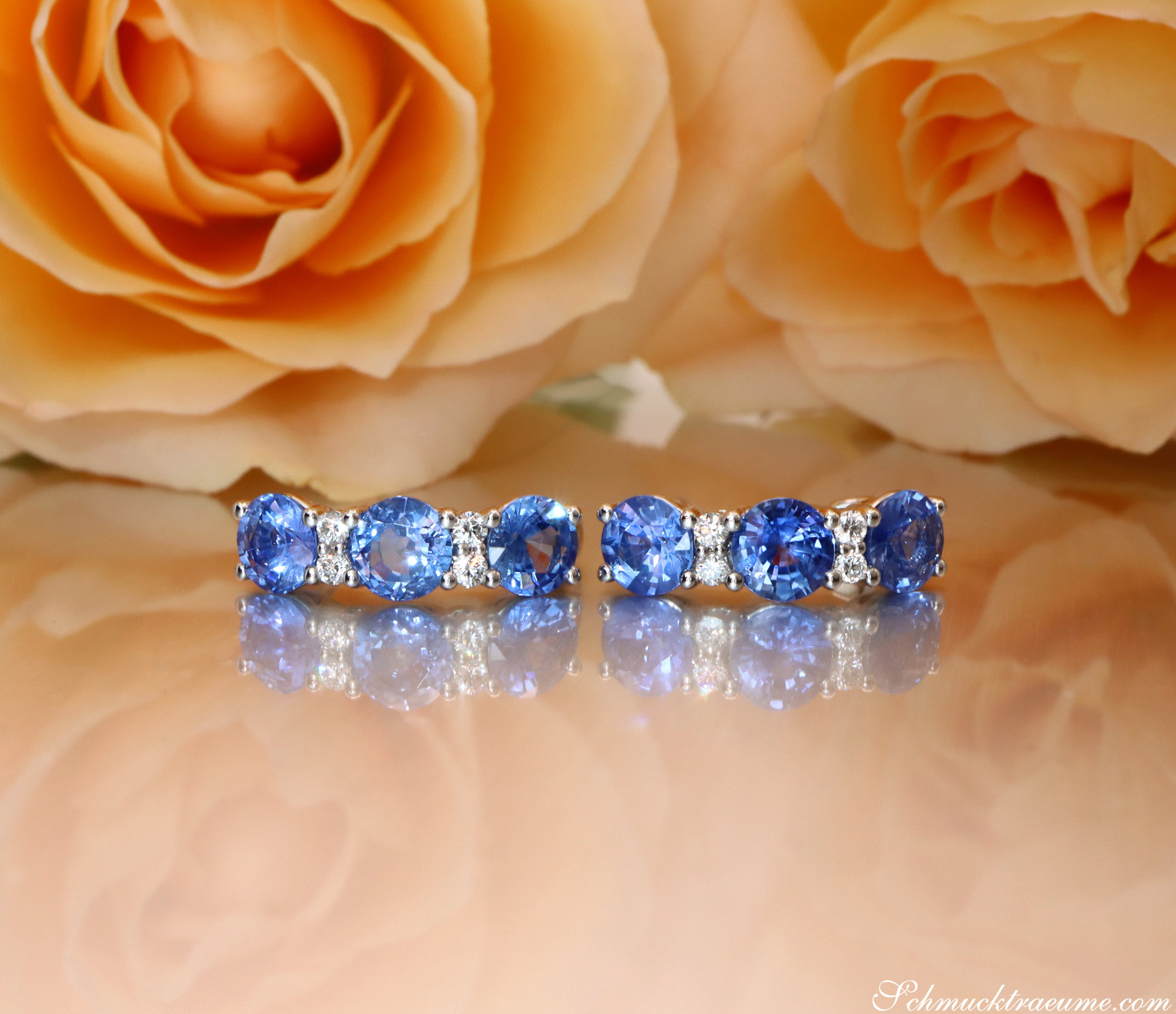 Blauer Saphir-Ohrring mit Brillanten in Weißgold, vor Rosenblüten