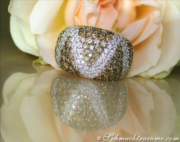 Zick-Zack-Ring mit naturbraunen & weißen Brillanten, goldene Akzente, Rosen im Hintergrund.