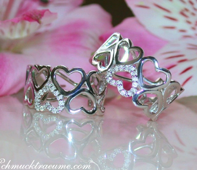 Herzformige Diamant-Ohrstecker im Weißgold 585, dezent elegant, vor rosa Blüten. Herzformige Diamant-Ohrstecker im Weißgold 585, dezent elegant, vor rosa Blüten.