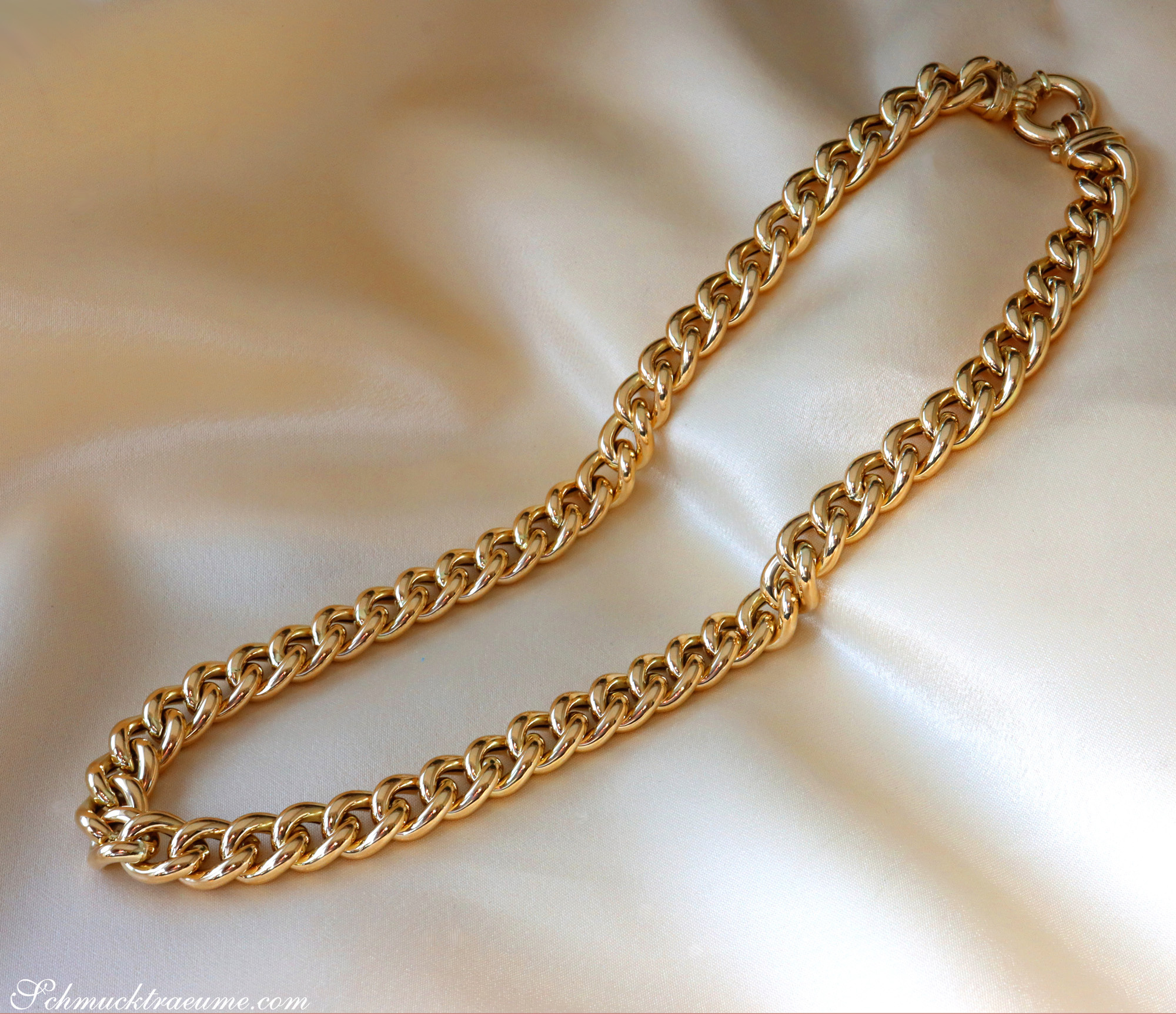 Goldene Panzerkette in Gelbgold 585 auf cremefarbenem Stoff, glänzender Schmuckdetail.