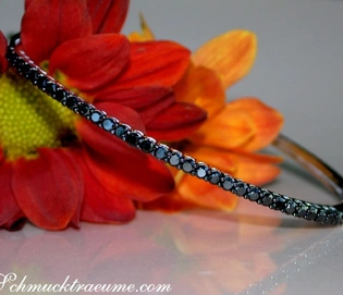 Schwarzer Diamant-Armreif in Weißgold, Detailaufnahme mit Blumenhintergrund