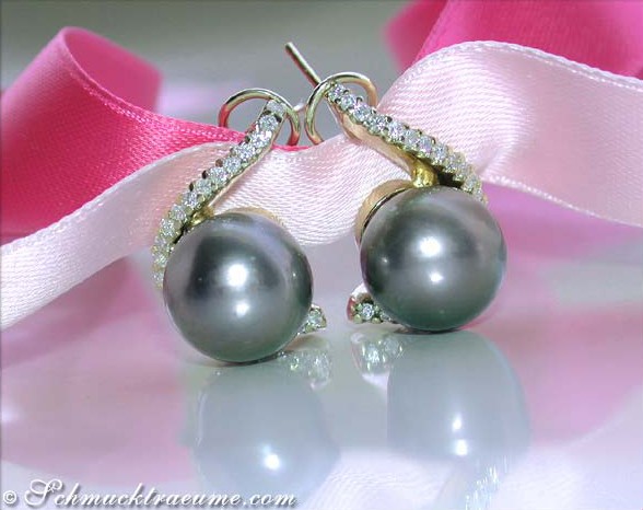 Schlichte Tahitiperlen-Ohrstecker mit Brillanten in Gelbgold, Detailaufnahme auf rosa Seide