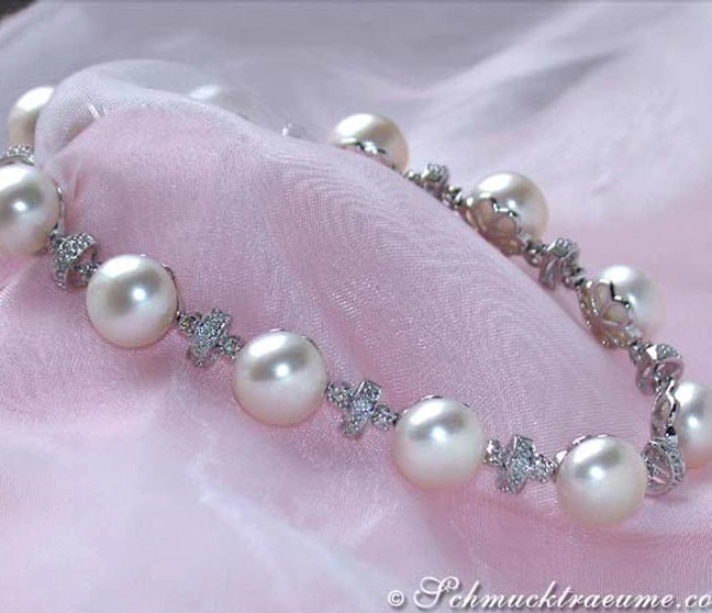 Weißgold-Armband mit Zuchtperlen und Diamanten auf rosa Stoff. Weißgold-Armband mit Zuchtperlen und Diamanten auf rosa Stoff.