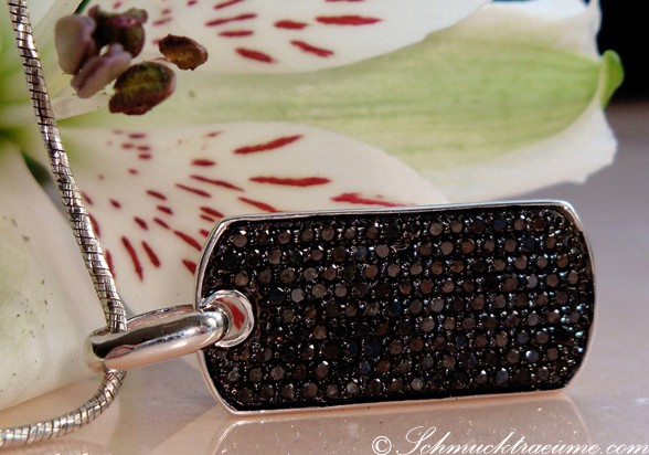 Silberner Dog Tag mit schwarzen Diamanten, Detailaufnahme, getragen auf weißem Blütenblatt