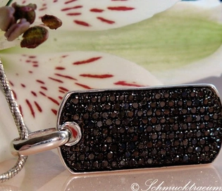 Silberner Dog Tag mit schwarzen Diamanten, Detailaufnahme, getragen auf weißem Blütenblatt