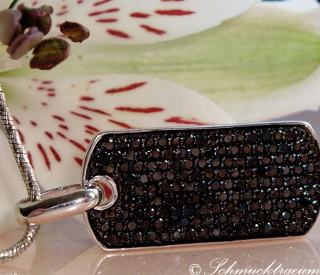 Silberner Dog Tag mit schwarzen Diamanten, Detailaufnahme, getragen auf weißem Blütenblatt Silberner Dog Tag mit schwarzen Diamanten, Detailaufnahme, getragen auf weißem Blütenblatt