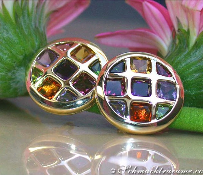 Goldene Ohrstecker mit bunten Edelsteinen auf glänzender Oberfläche Goldene Ohrstecker mit bunten Edelsteinen auf glänzender Oberfläche