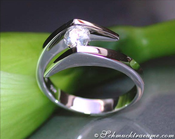 Detailansicht des Zeitlosen Diamant Solitär Rings in Weißgold 750, funkelndes Brillant, schlichte Form, grüne Pflanze im