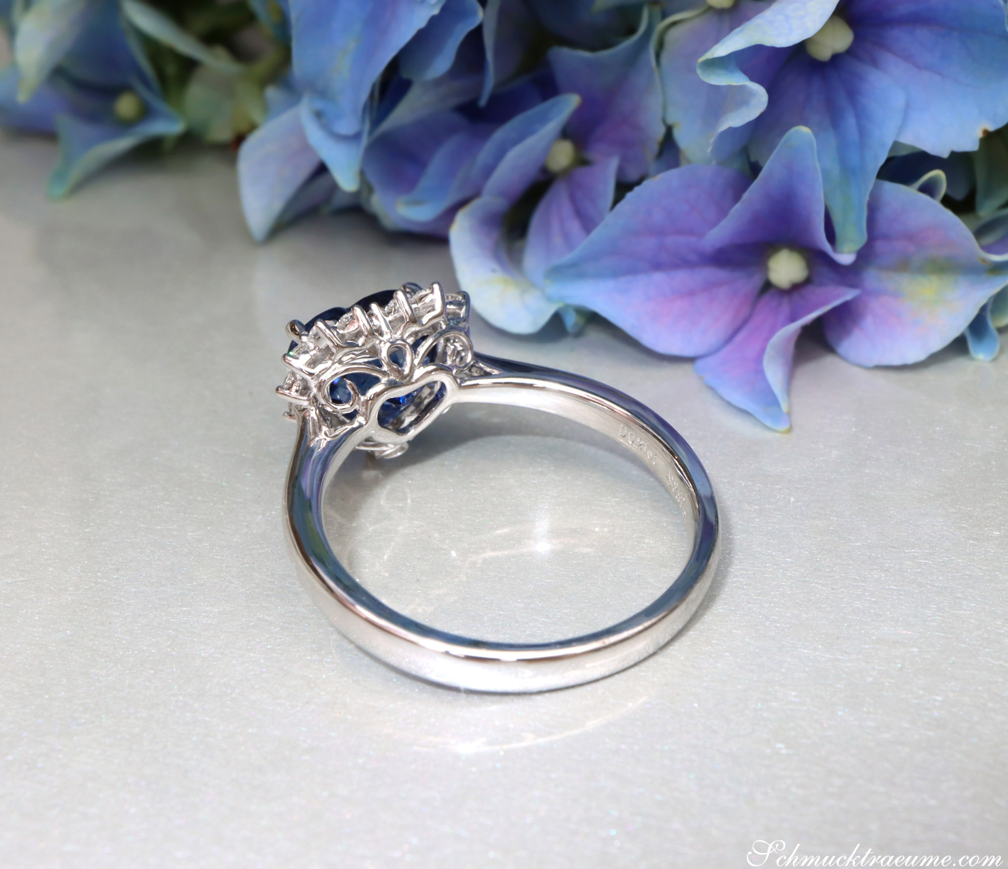 Silberner Saphir Herz-Ring mit Brillanten, Detailaufnahme, blühende Hortensien im Hintergrund.