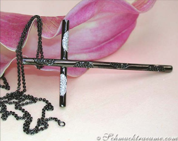 Schwarzer Diamantkreuzanhänger auf Kette, Detailaufnahme mit Blume im Hintergrund