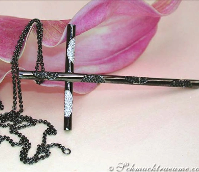 Schwarzer Diamantkreuzanhänger auf Kette, Detailaufnahme mit Blume im Hintergrund Schwarzer Diamantkreuzanhänger auf Kette, Detailaufnahme mit Blume im Hintergrund