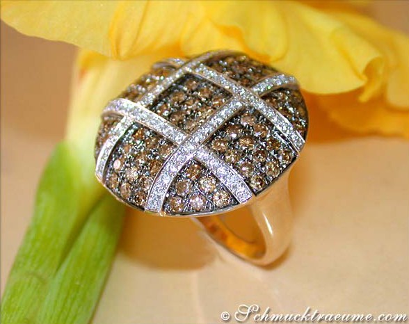 Gelbgoldring mit naturbraunen und weißen Brillanten, Detailaufnahme, Blume im Hintergrund