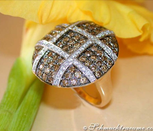 Gelbgoldring mit naturbraunen und weißen Brillanten, Detailaufnahme, Blume im Hintergrund Gelbgoldring mit naturbraunen und weißen Brillanten, Detailaufnahme, Blume im Hintergrund