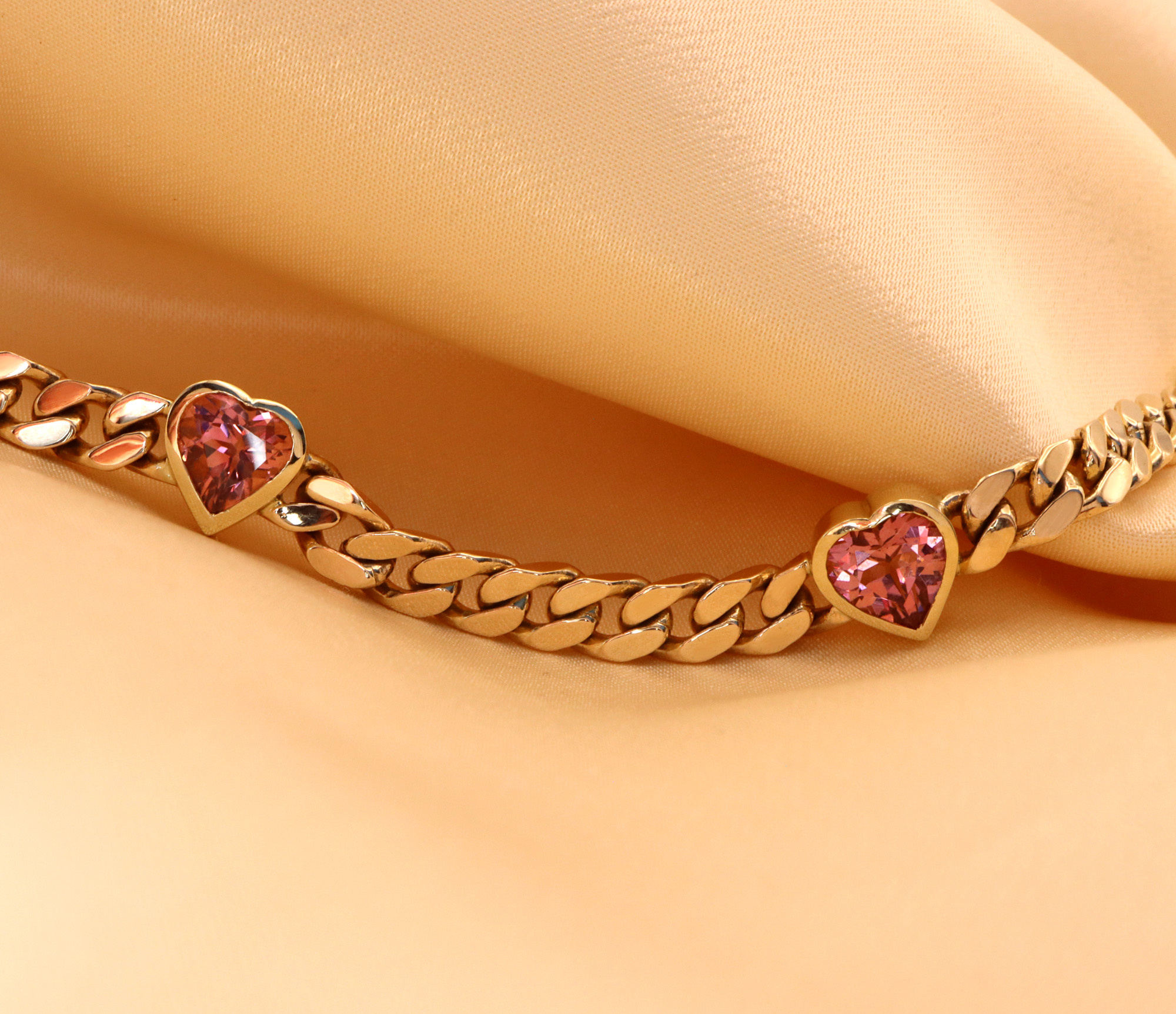 Goldene Panzerarmband mit rosa Herzen auf samtigem Hintergrund