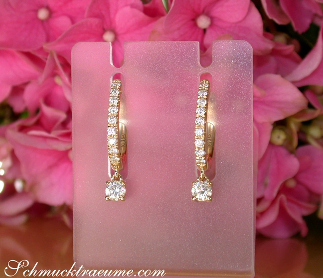 Pinkes Display mit eleganten Creolen mit Brillanten, Hintergrund aus rosa Blüten. Pinkes Display mit eleganten Creolen mit Brillanten, Hintergrund aus rosa Blüten.