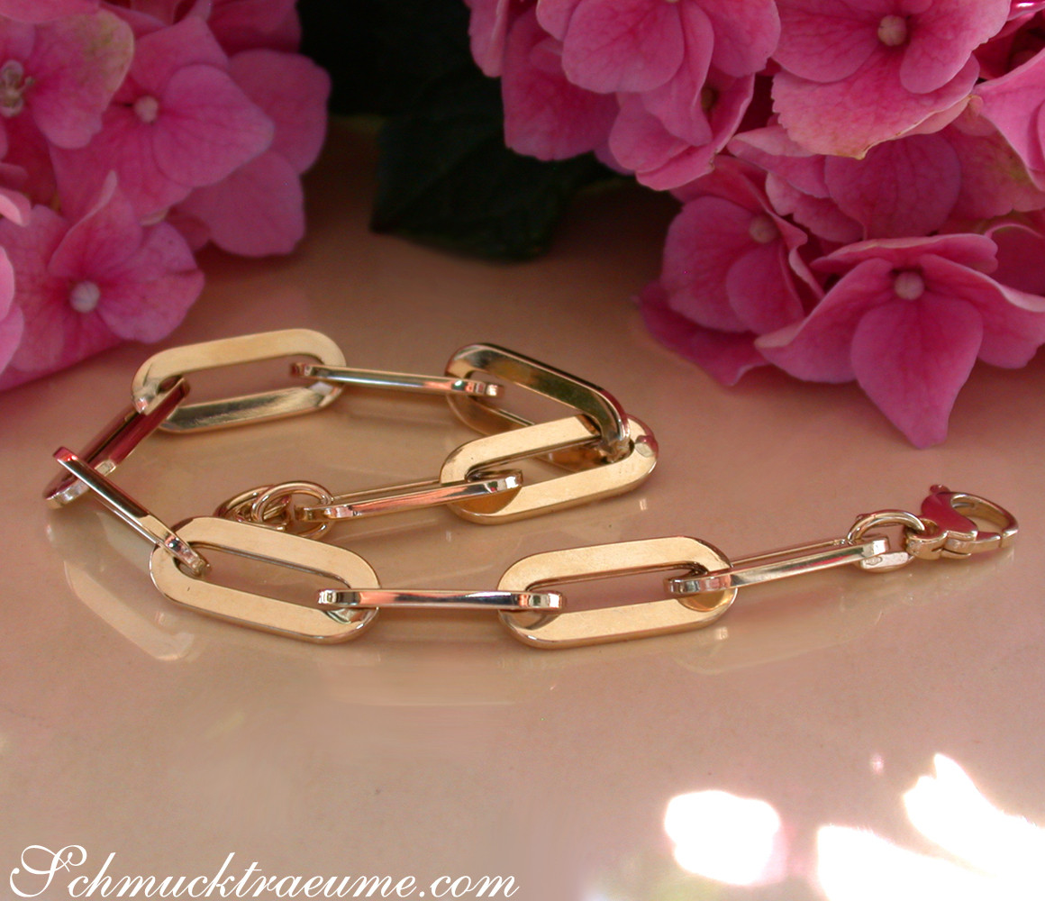 Goldenes Paperclip-Armband auf rosa Hortensienblüten im Sonnenlicht