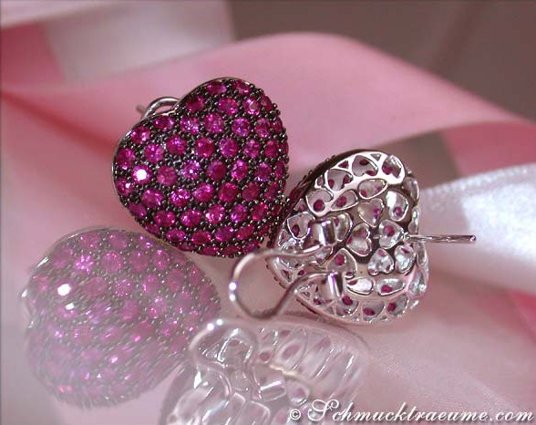 Weißgold Herz-Ohrringe mit Rubinen, detailreich, elegant auf rosa Schleife.