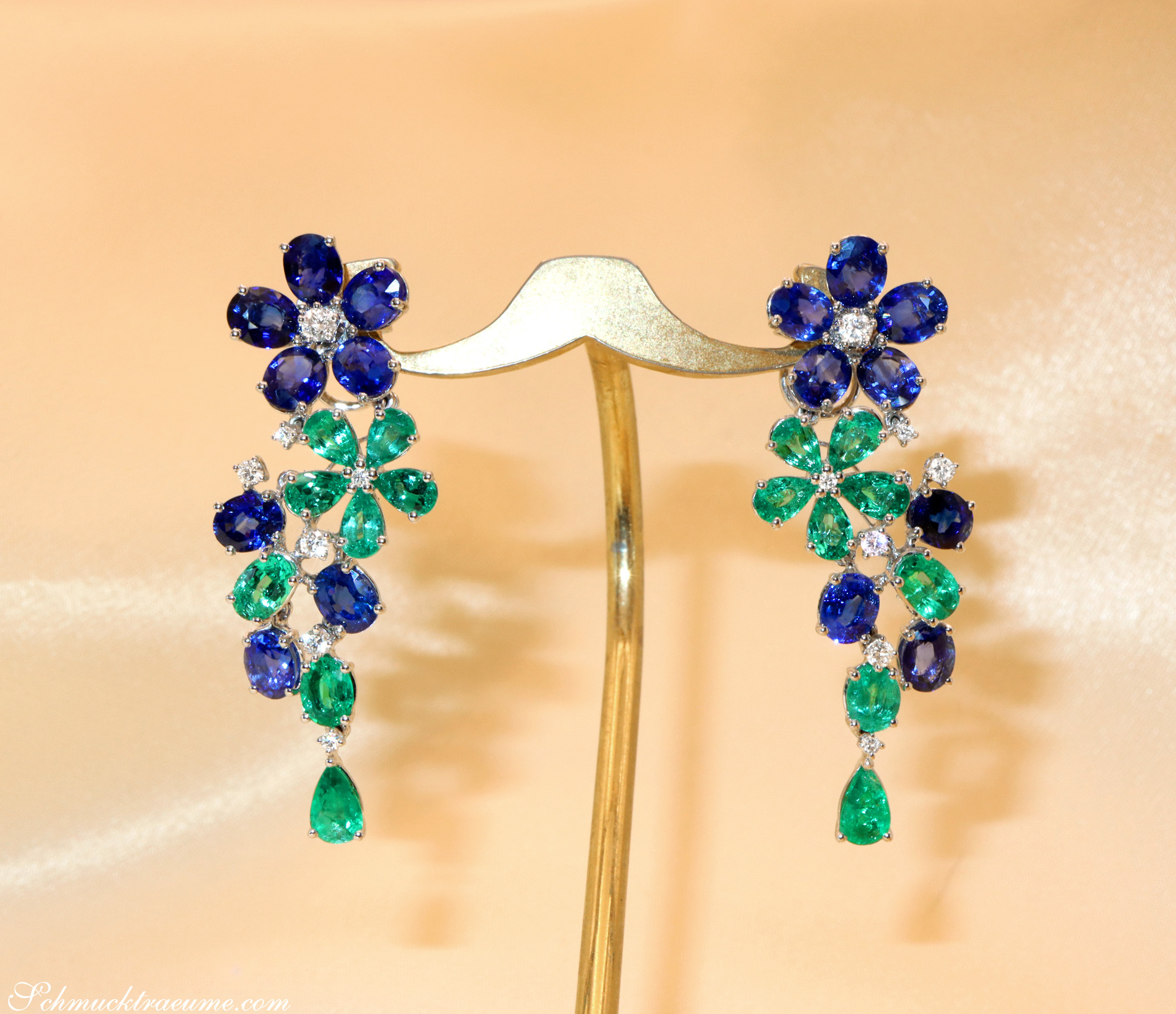 Blumenformige Ohrschmuck mit Smaragden und Saphiren, präsentiert auf Goldständer