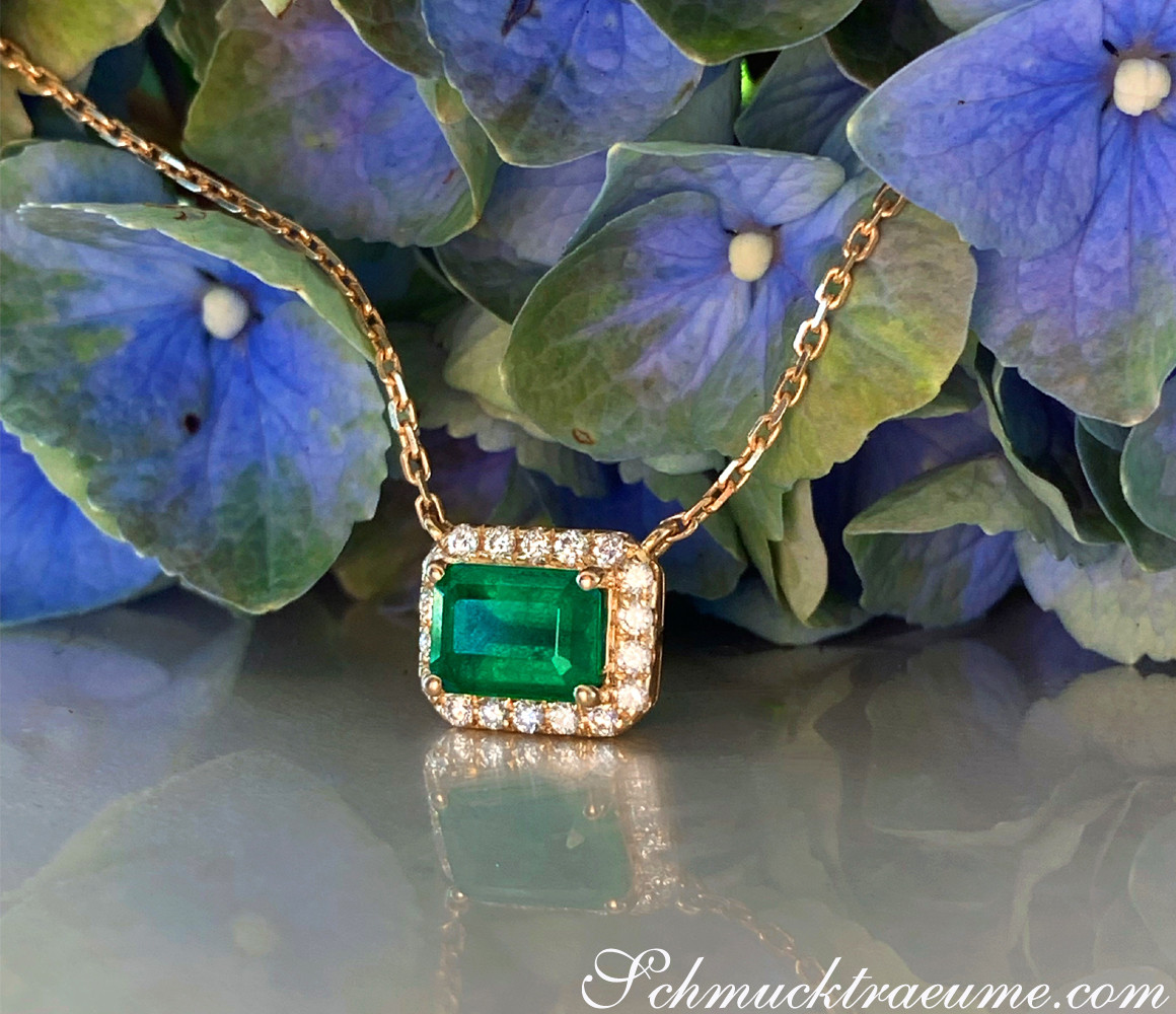 Goldene Kette mit Smaragd und Diamanten auf Blumenhintergrund