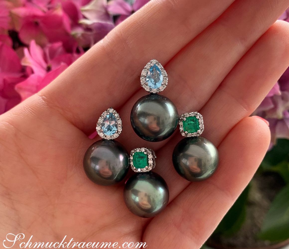 Perlenohrringe mit Aquamarin und Diamanten auf der Hand, Hintergrund mit Blüten