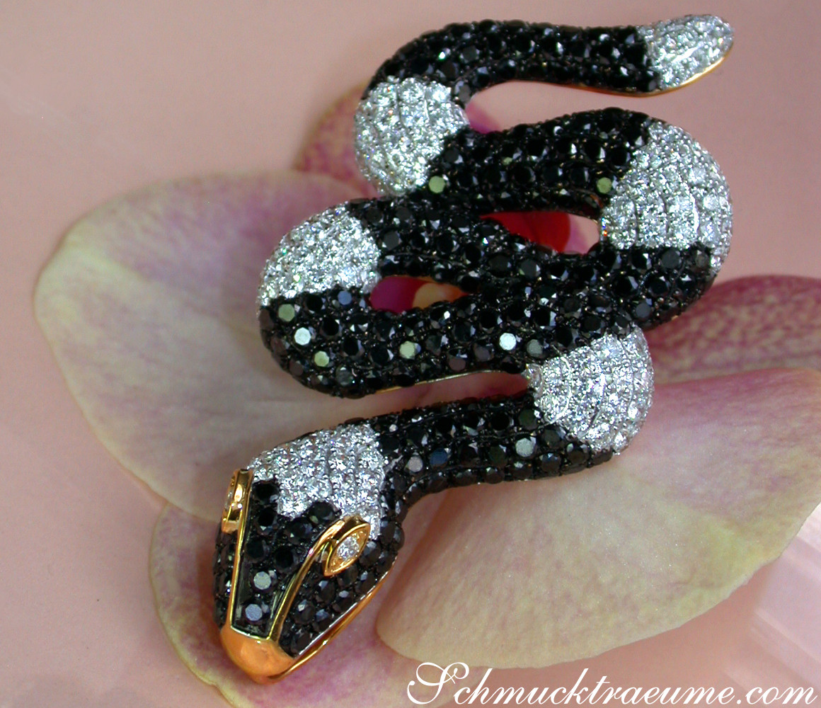 Schlangenanhänger aus Gelbgold mit schwarzen und weißen Diamanten, detailreich getragen.