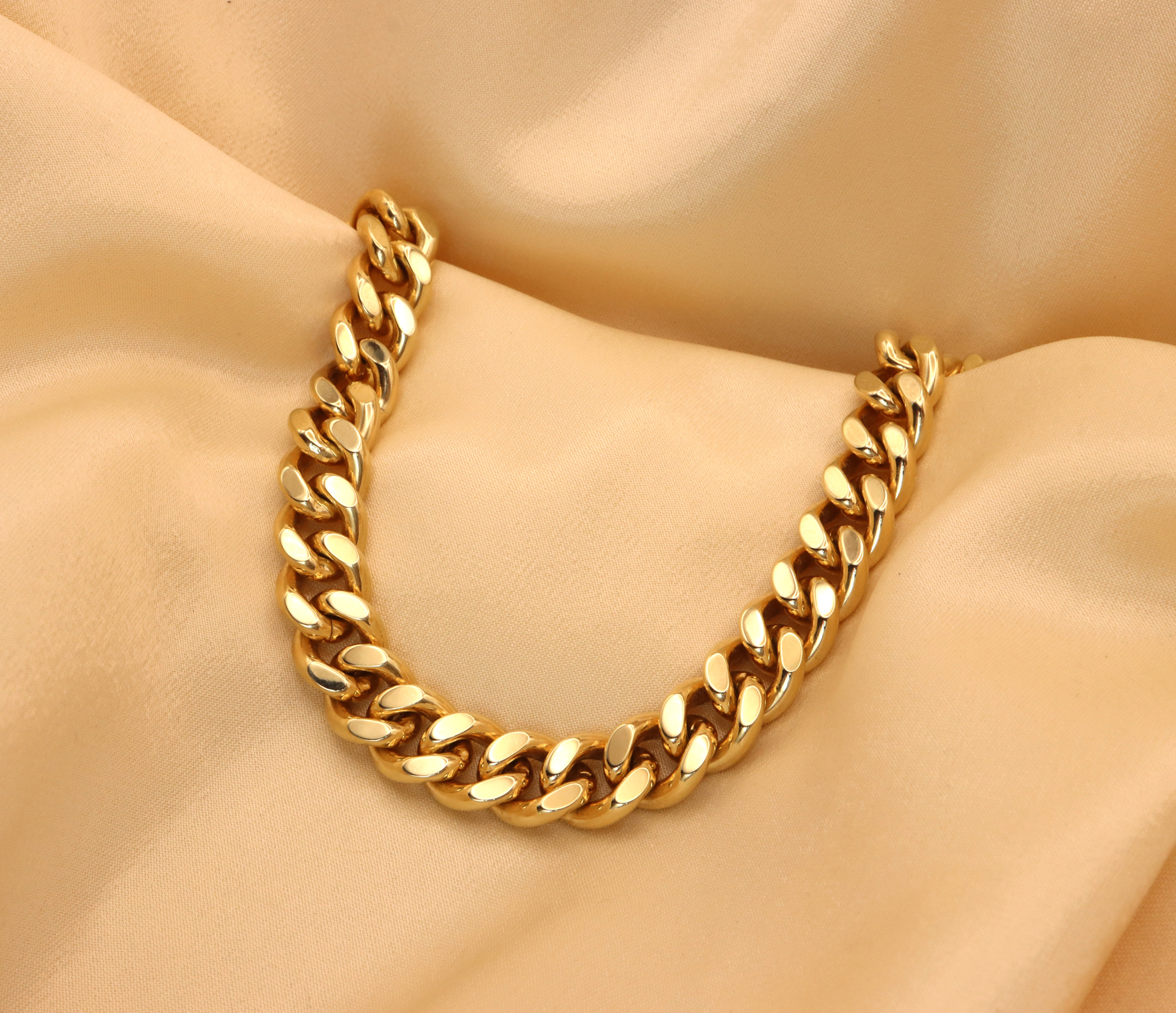 Goldene Panzerarmband-Art in Gelbgold 585, Detailaufnahme auf cremefarbenem Stoff, luxuriöses Design.