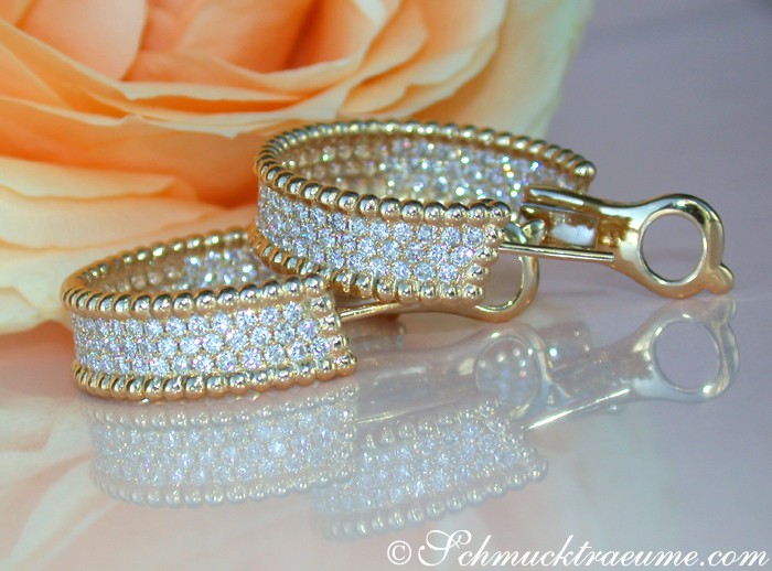 Goldene Creolen mit Diamanten, Detailaufnahme, elegant, glänzend, auf Blüte.