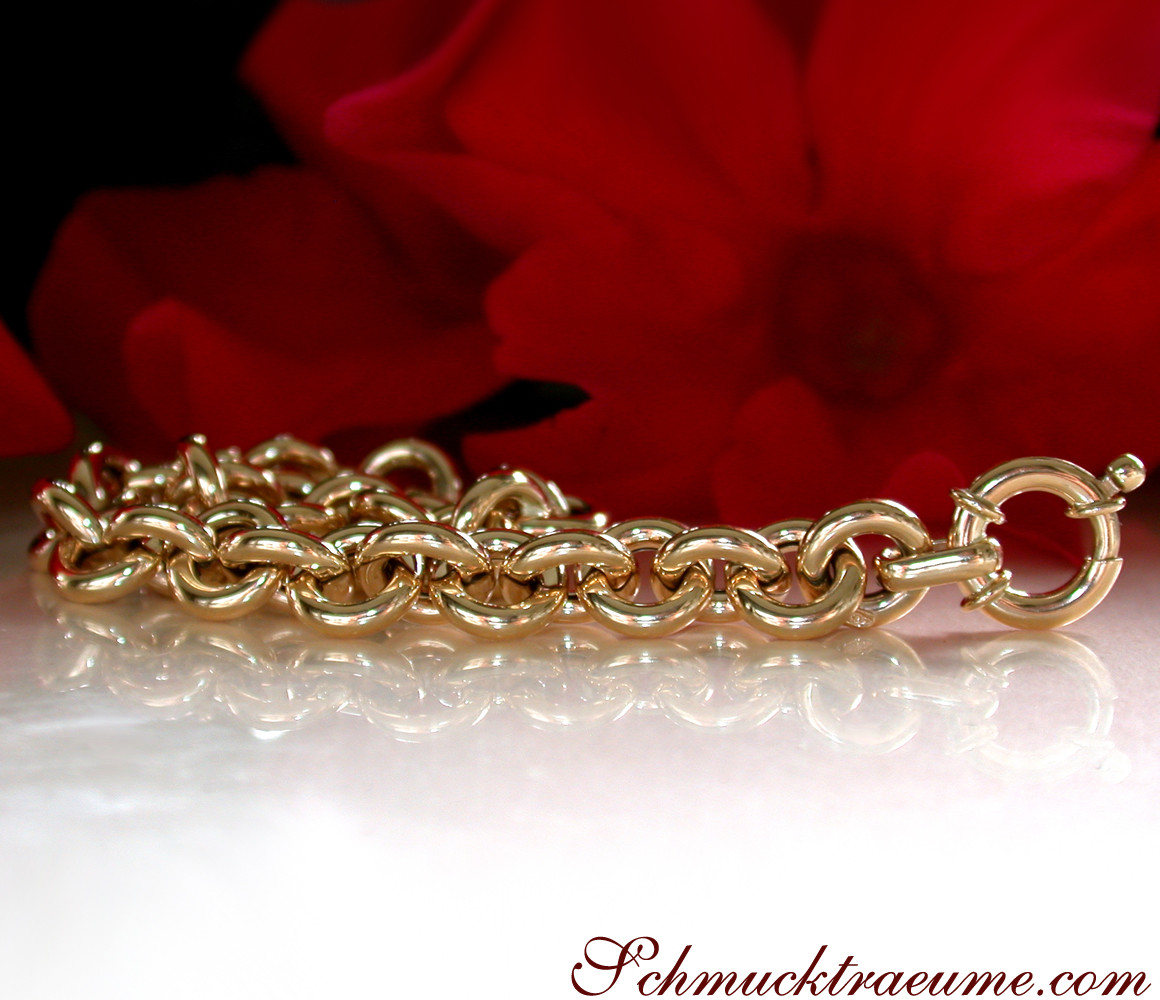 Goldarmband mit glänzenden Ringelementen vor rotem Hintergrund