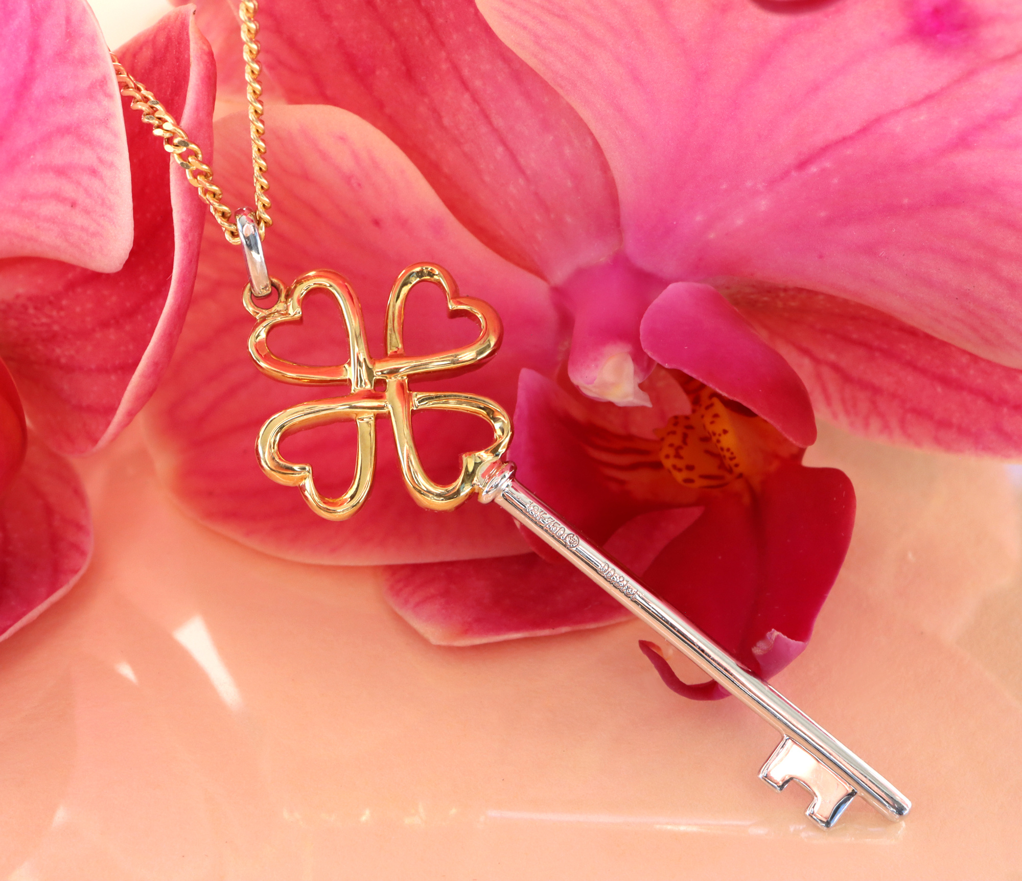 Goldener Schlüssel-Anhänger mit vier Herzen auf Blüte, Detailaufnahme.