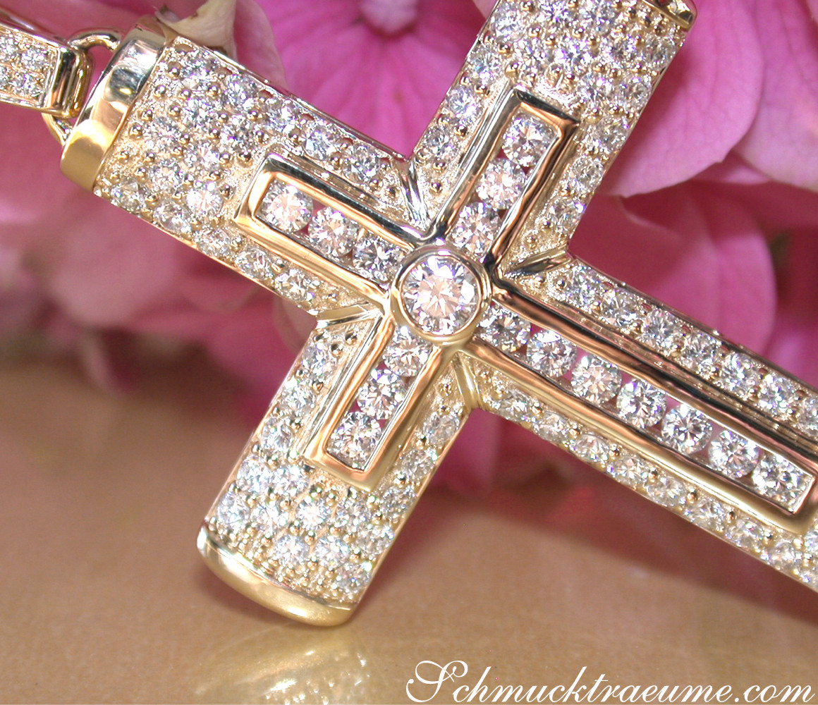 Goldener Kreuzanhänger mit Brillanten, Detailaufnahme, getragen auf rosa Blüte