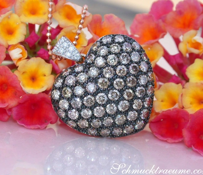 Herz-Anhänger mit naturbraunen Brillanten, roségold, detailreich, vor Blüten. Herz-Anhänger mit naturbraunen Brillanten, roségold, detailreich, vor Blüten.