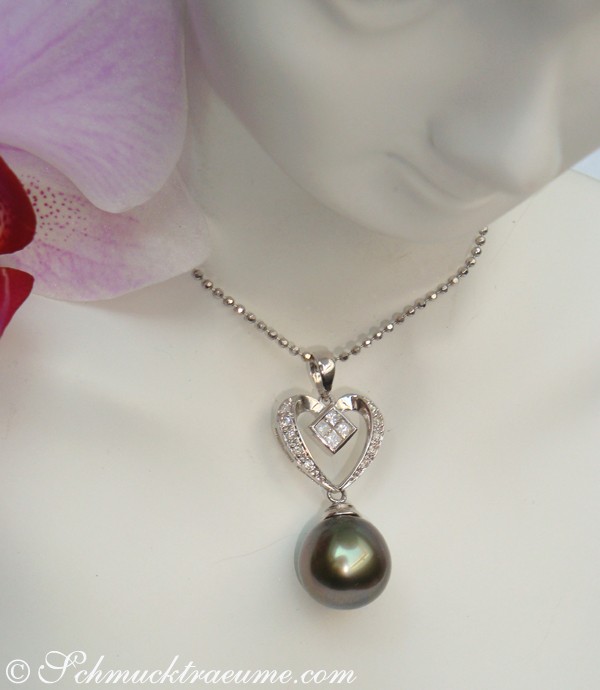 Herz-Anhänger mit Tahitiperle und Diamanten, Detailaufnahme, zarte Kette, Blume im Hintergrund