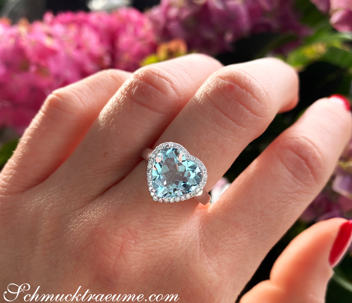 Weißgold Herzring mit Aquamarin und Diamant-Halo auf Blumenhintergrund