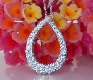 Teardrop-Diamantanhänger mit Perlenbesatz vor Blütenhintergrund