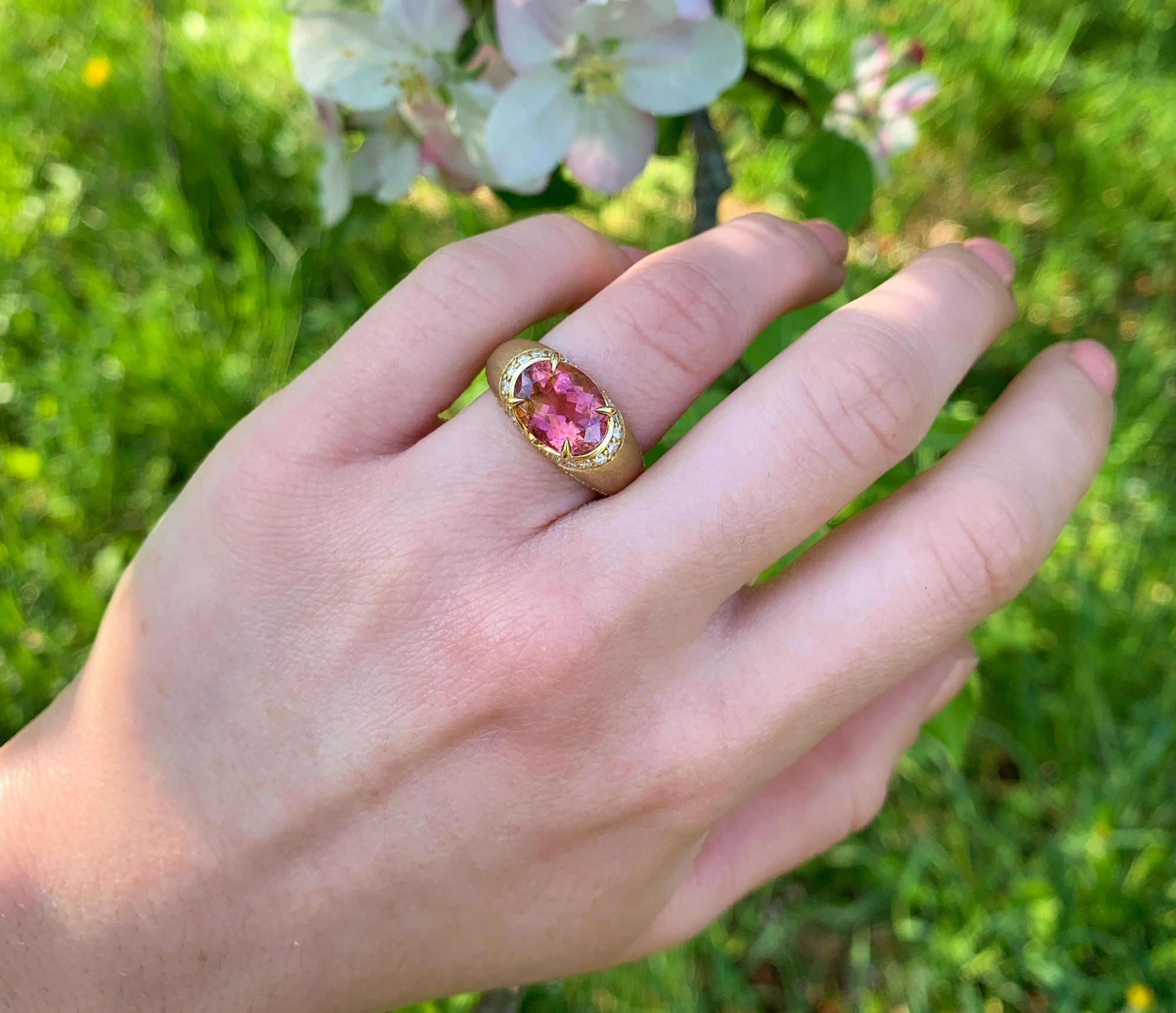 Goldener Turmalin-Ring auf grünem Hintergrund, Detailaufnahme.