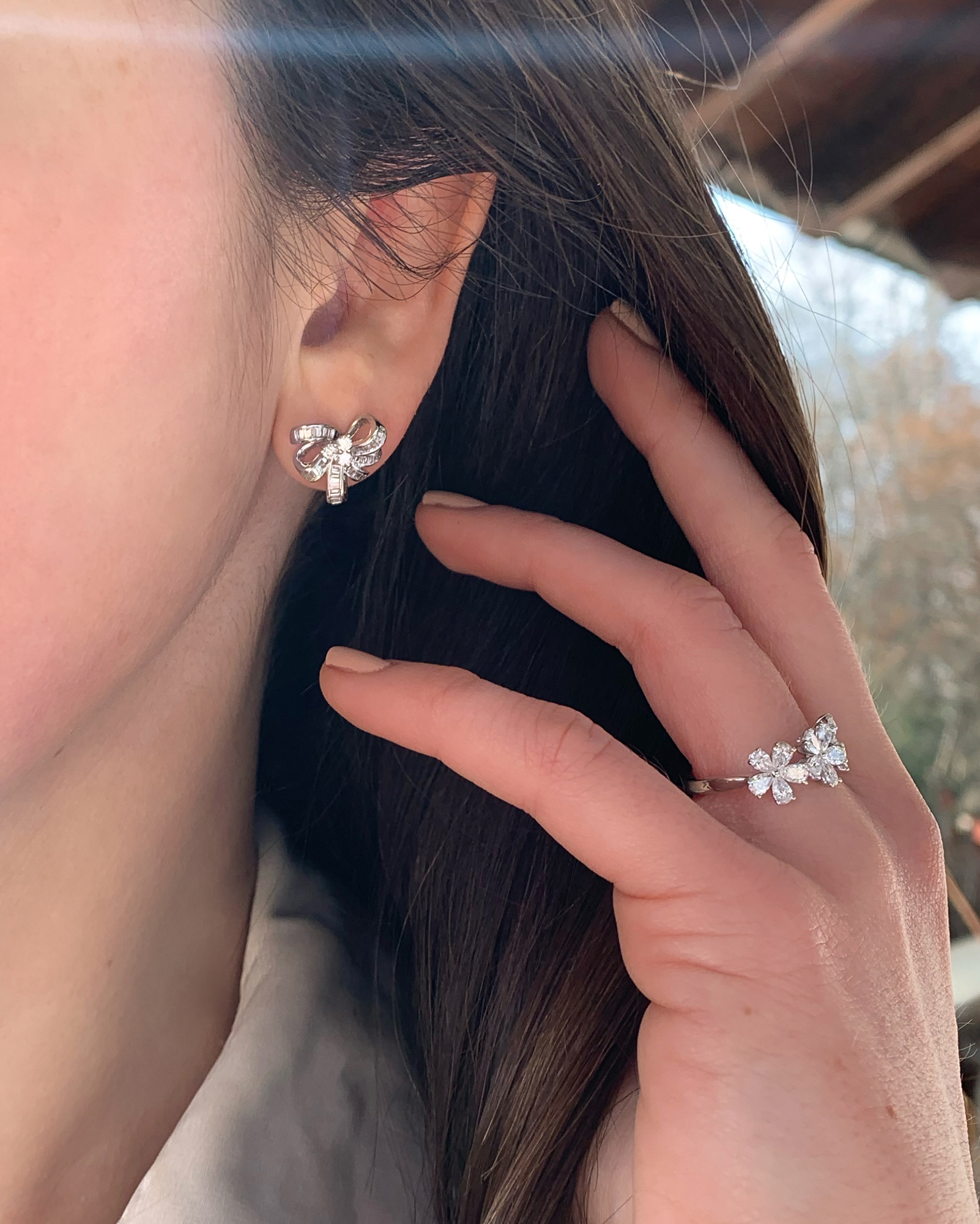 Weißgold Ohrstecker mit Diamantenschleife, Detailaufnahme, Frau trägt Ohrstecker und Ring