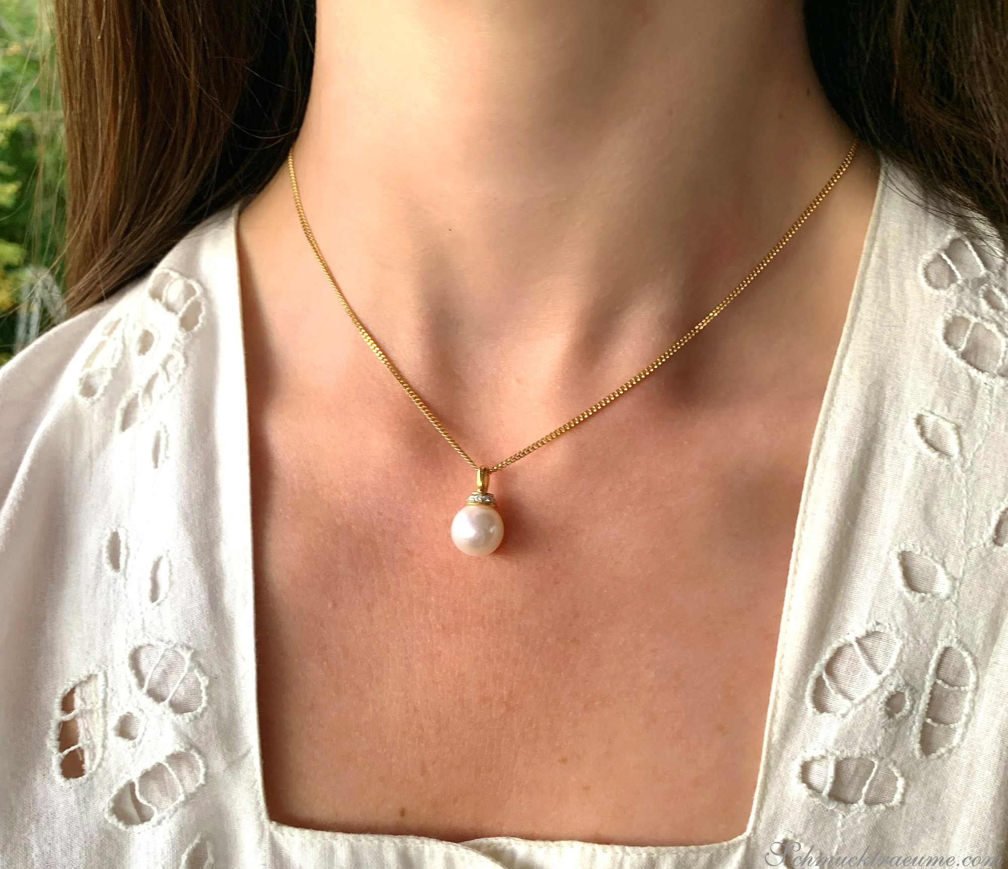 Goldkette mit Perlenanhänger und Brillanten, getragen unter weißem Blusenärmel