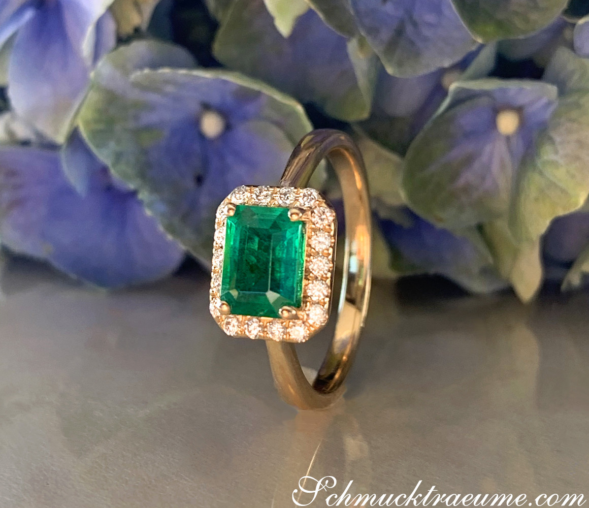 Goldener Smaragd-Ring mit Brillanten, detailreich, blühende Blüten im Hintergrund
