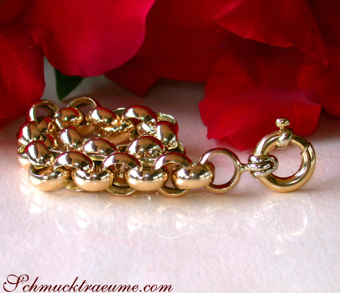 Goldarmband aus Gelbgold 585 mit funkelnden Ringen, Rosenblüte im Hintergrund