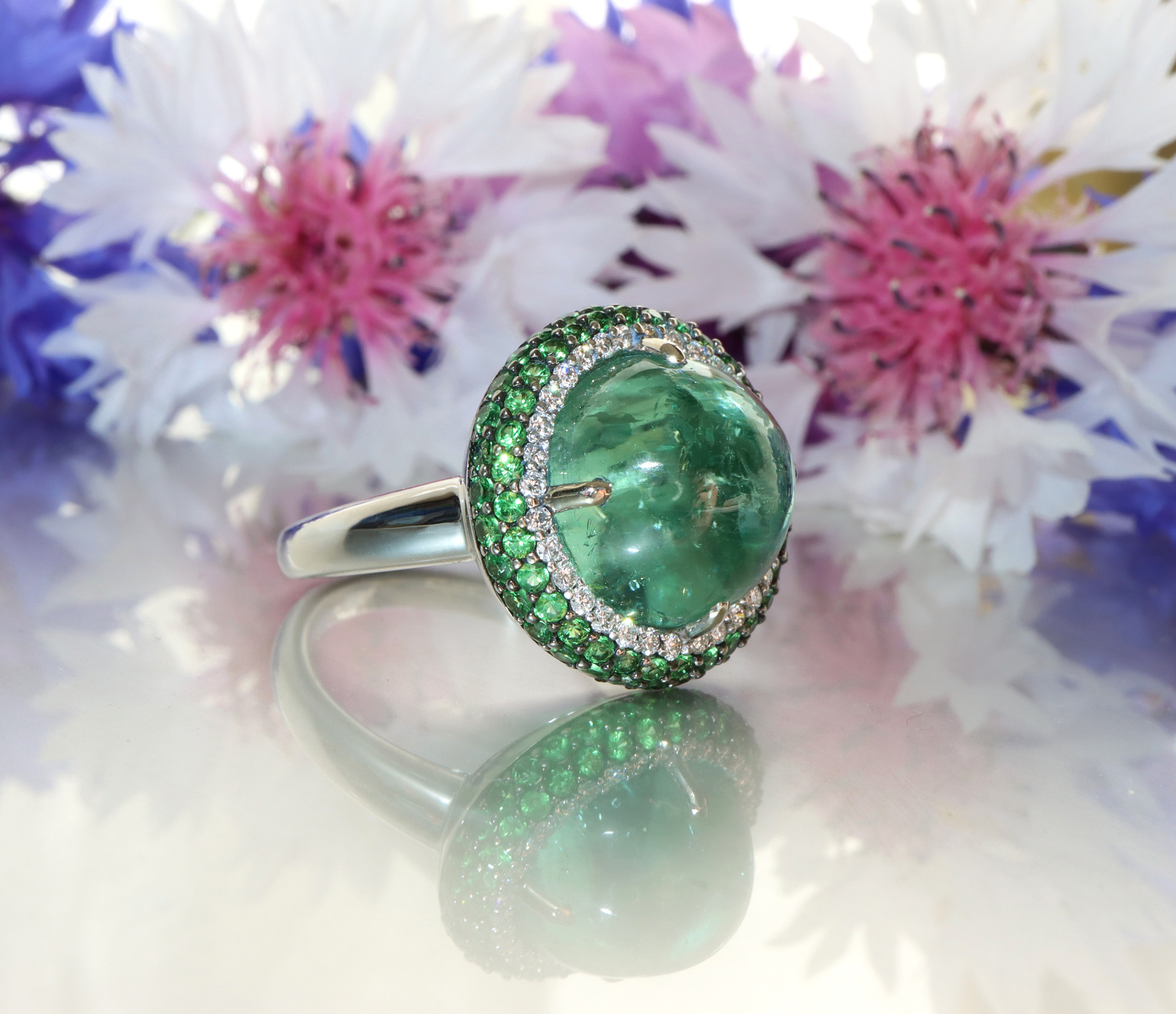 Minz-Turmalin-Ring mit Tsavorite und Brillanten, detailreich, blühende Blumen im Hintergrund