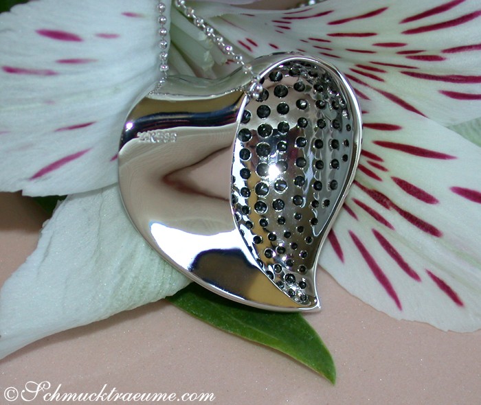 Schwarzer Diamant-Herz-Anhänger mit Perlen auf silberner Kette, umgeben von Blütenblättern.